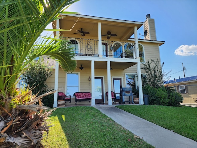 view of front of home featuring a balcony, ceiling fan, a front yard, and a patio area