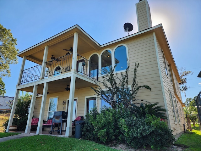 rear view of house featuring ceiling fan and a balcony