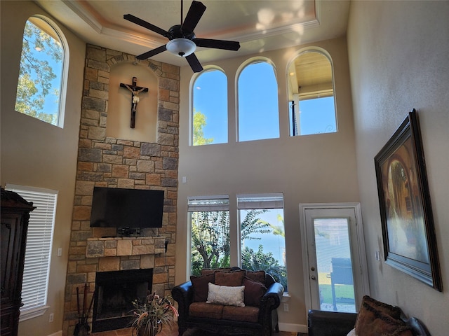 living room with a fireplace, a healthy amount of sunlight, a raised ceiling, and crown molding