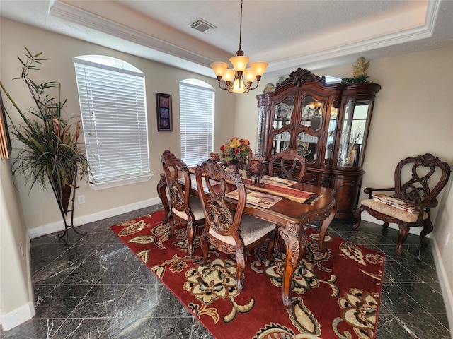 dining room featuring a chandelier, a textured ceiling, a tray ceiling, and ornamental molding