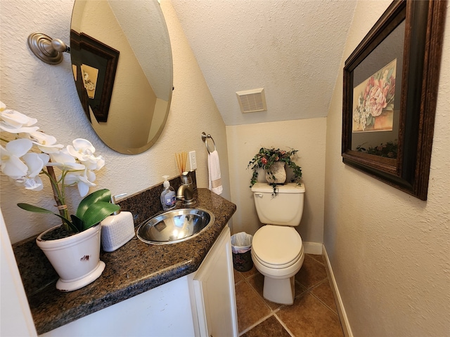 bathroom featuring toilet, vanity, a textured ceiling, and tile patterned flooring