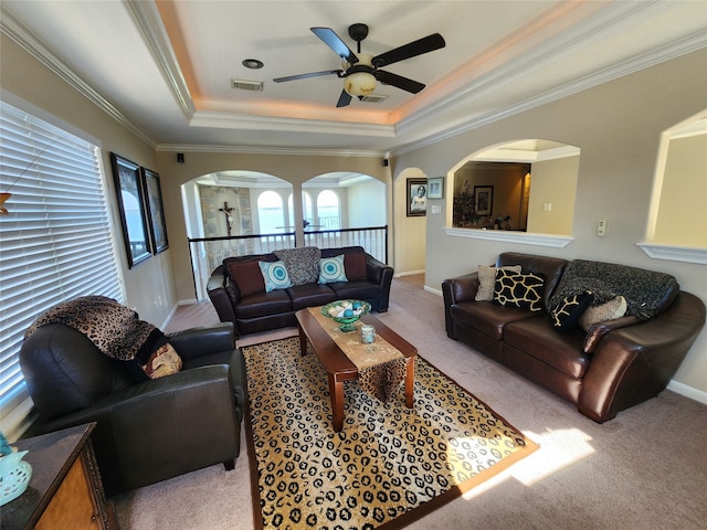 living room with a tray ceiling, light colored carpet, ceiling fan, and crown molding