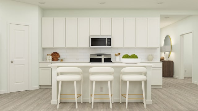 kitchen featuring stainless steel appliances, white cabinets, light wood-type flooring, and decorative backsplash