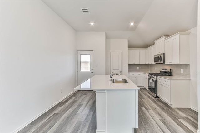 kitchen with light hardwood / wood-style floors, sink, appliances with stainless steel finishes, an island with sink, and white cabinets