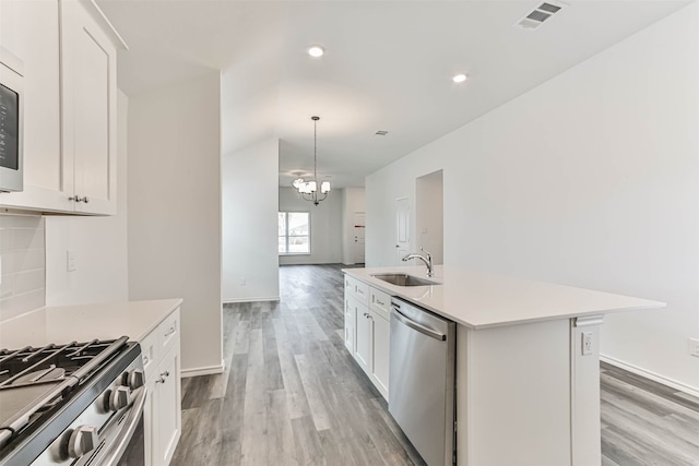 kitchen featuring white cabinets, stainless steel appliances, and an island with sink