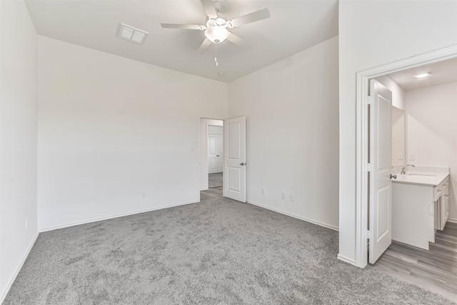 unfurnished bedroom featuring ceiling fan, ensuite bath, sink, and carpet floors