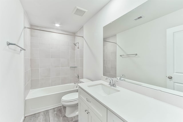 full bathroom with wood-type flooring, tiled shower / bath combo, toilet, and vanity