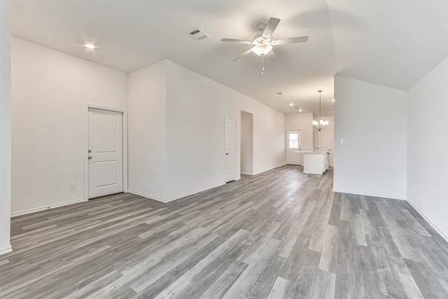 unfurnished living room with ceiling fan with notable chandelier and wood-type flooring