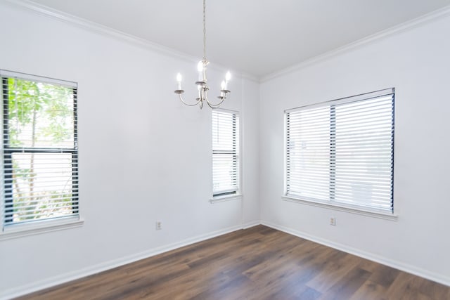 empty room featuring an inviting chandelier, plenty of natural light, crown molding, and dark hardwood / wood-style flooring