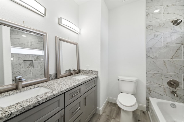 full bathroom with tiled shower / bath, vanity, toilet, and hardwood / wood-style flooring