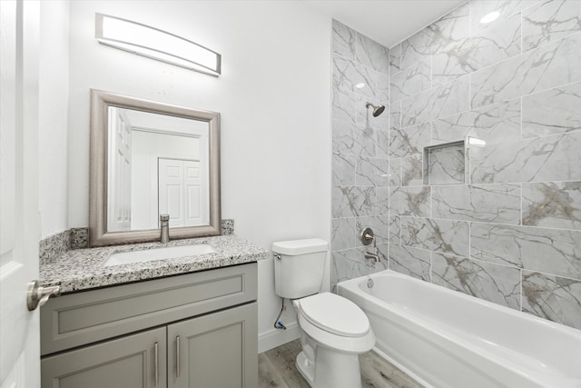 full bathroom featuring hardwood / wood-style flooring, vanity, toilet, and tiled shower / bath combo