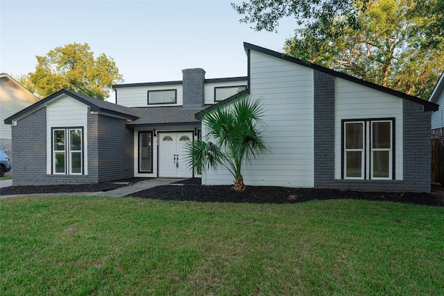 mid-century modern home featuring brick siding and a front yard