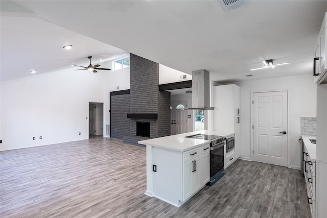 kitchen with plenty of natural light, island range hood, electric range, and white cabinets