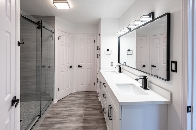 bathroom with an enclosed shower, wood-type flooring, and vanity