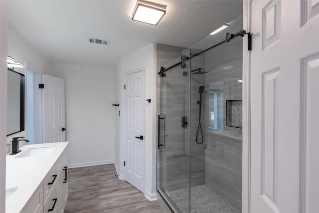 bathroom with vanity, hardwood / wood-style flooring, and a shower with shower door