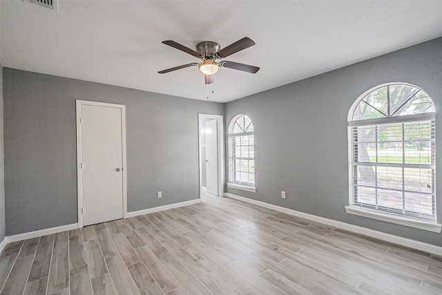 empty room featuring light hardwood / wood-style floors, a healthy amount of sunlight, and ceiling fan