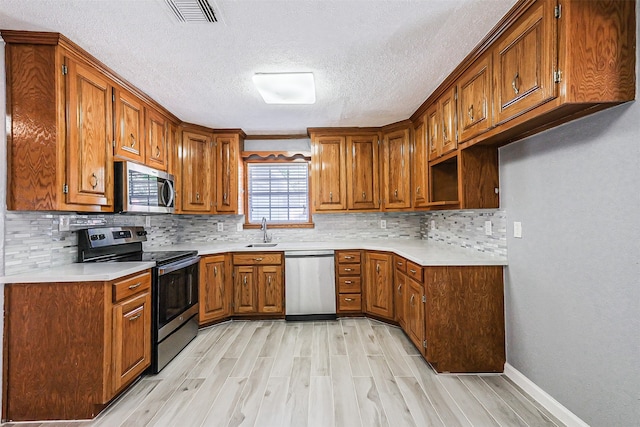 kitchen featuring light hardwood / wood-style floors, a textured ceiling, sink, tasteful backsplash, and appliances with stainless steel finishes