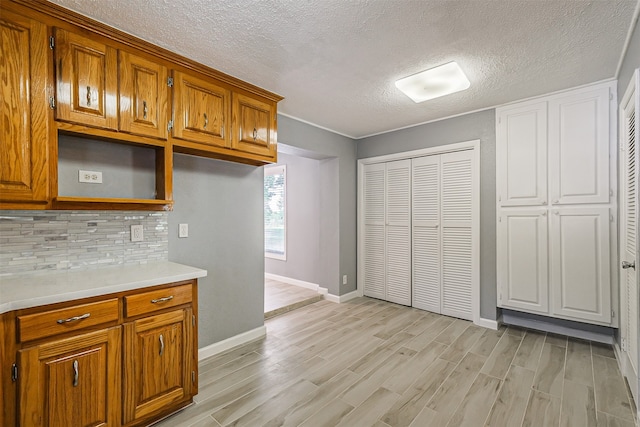 kitchen with light hardwood / wood-style floors, a textured ceiling, and backsplash