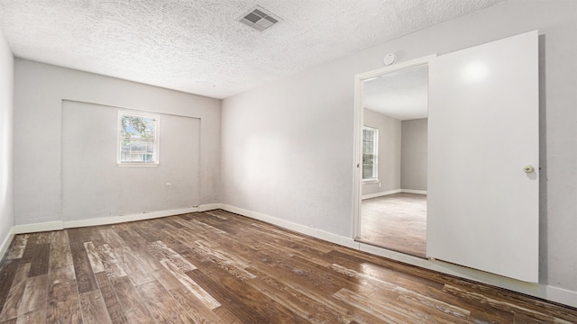 empty room with dark hardwood / wood-style flooring and a textured ceiling