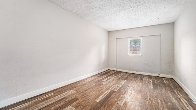 empty room featuring a textured ceiling and dark hardwood / wood-style floors