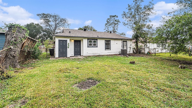 back of property with central AC and a lawn