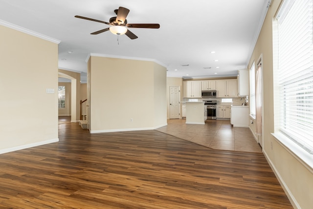 unfurnished living room featuring hardwood / wood-style floors, sink, and crown molding