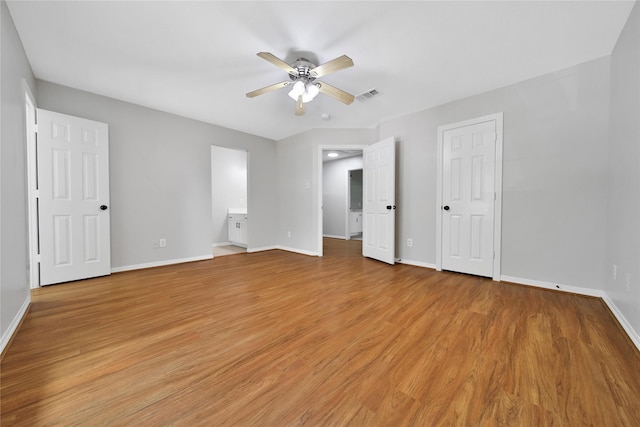 unfurnished bedroom featuring ensuite bath, light hardwood / wood-style flooring, and ceiling fan