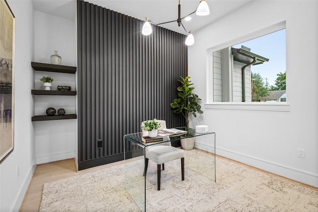 office with light wood-type flooring and a notable chandelier