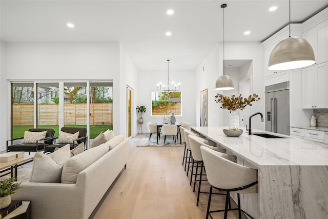 living room with sink, a notable chandelier, and light hardwood / wood-style flooring