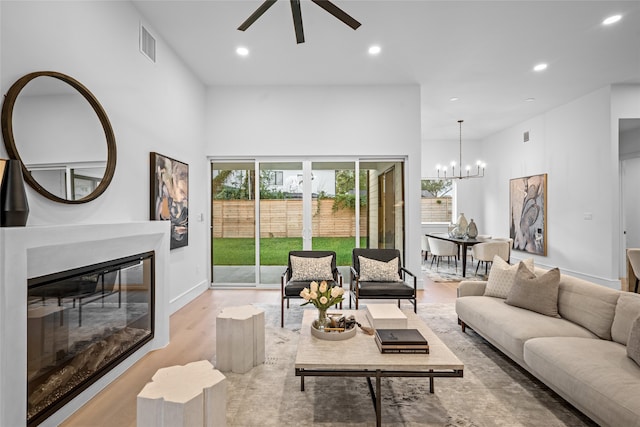 living room featuring light wood-type flooring and ceiling fan with notable chandelier