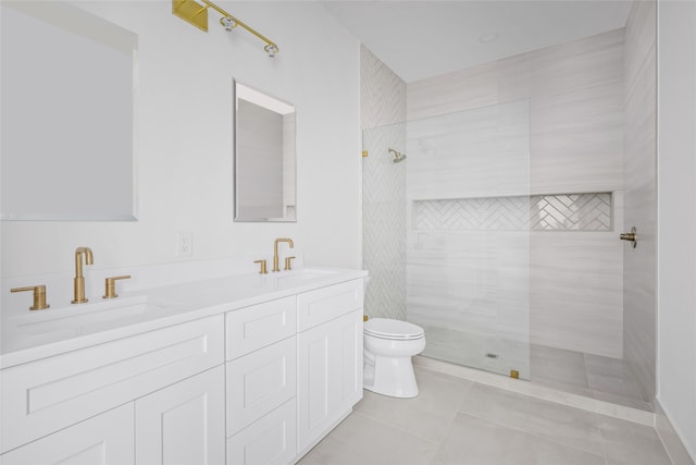 bathroom with toilet, tiled shower, vanity, and tile patterned floors