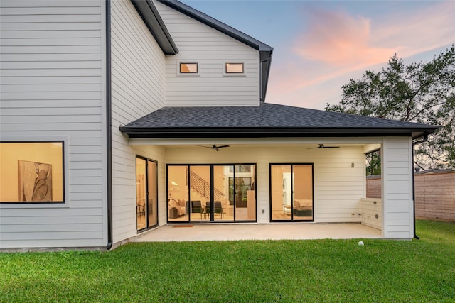 back house at dusk featuring a patio area, a yard, and ceiling fan