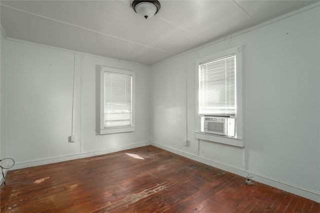 empty room featuring a wealth of natural light, dark wood-type flooring, and cooling unit