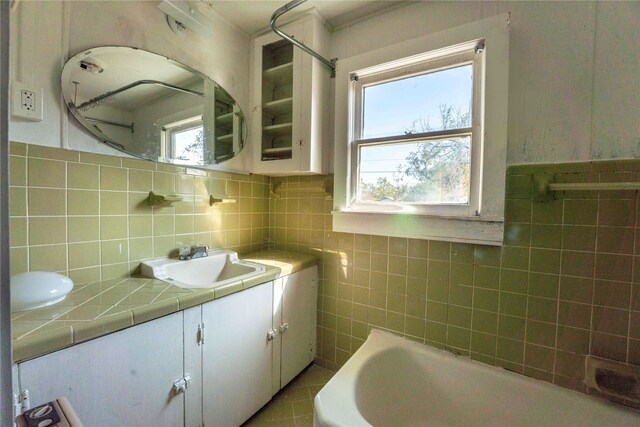 bathroom featuring a bathtub, vanity, and tile walls