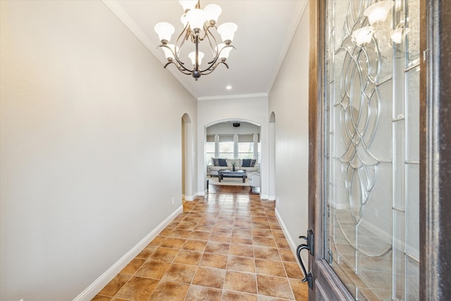 corridor with ornamental molding and an inviting chandelier