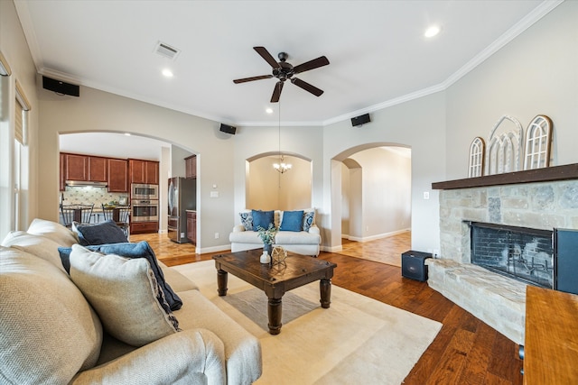 living room featuring a fireplace, ceiling fan with notable chandelier, light hardwood / wood-style flooring, and ornamental molding