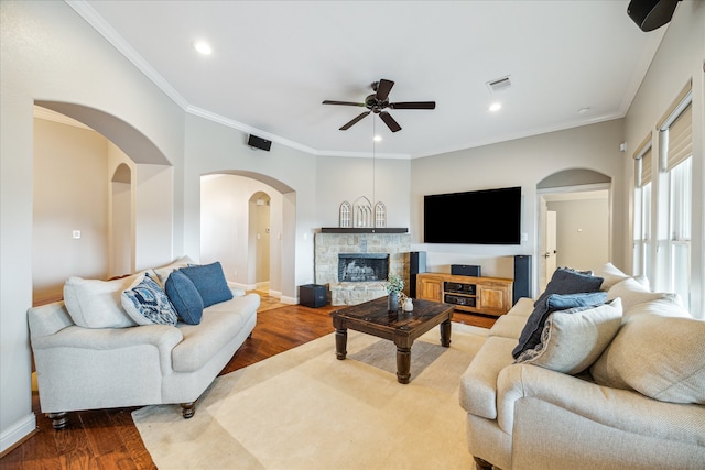 living room with ceiling fan, a fireplace, wood-type flooring, and ornamental molding