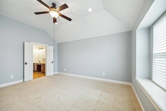 unfurnished bedroom featuring light carpet, ensuite bath, ceiling fan, and lofted ceiling