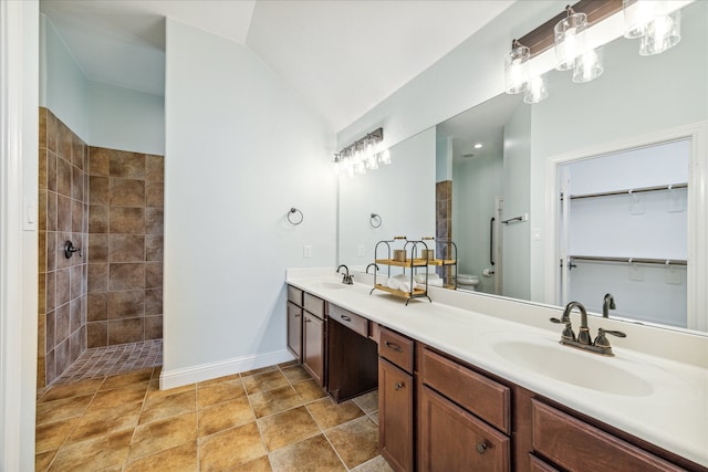 bathroom with tiled shower, vanity, lofted ceiling, and toilet