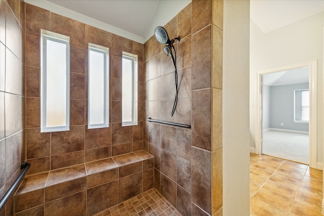 bathroom featuring a tile shower, plenty of natural light, and vaulted ceiling