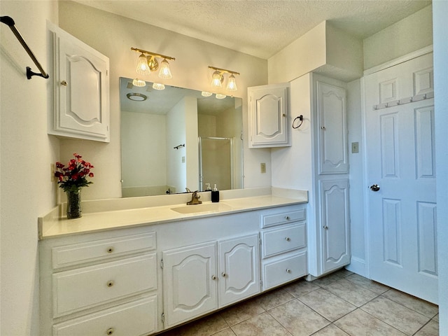 bathroom featuring tile patterned flooring, an enclosed shower, vanity, and a textured ceiling