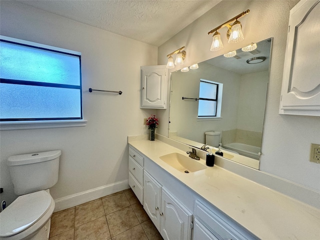 bathroom featuring tile patterned floors, vanity, a textured ceiling, a bathing tub, and toilet