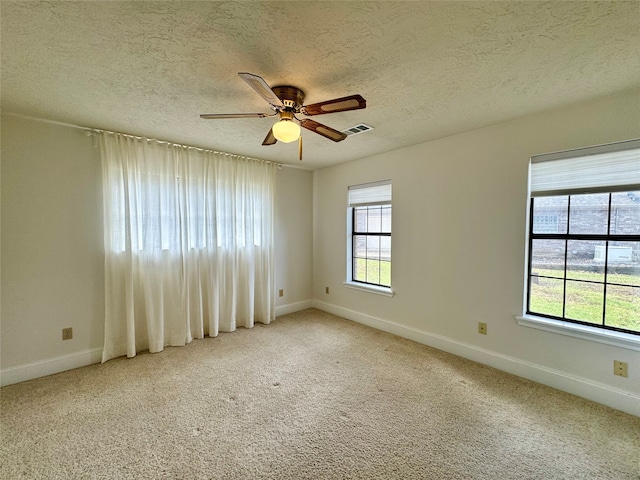 carpeted empty room with ceiling fan, a healthy amount of sunlight, and a textured ceiling