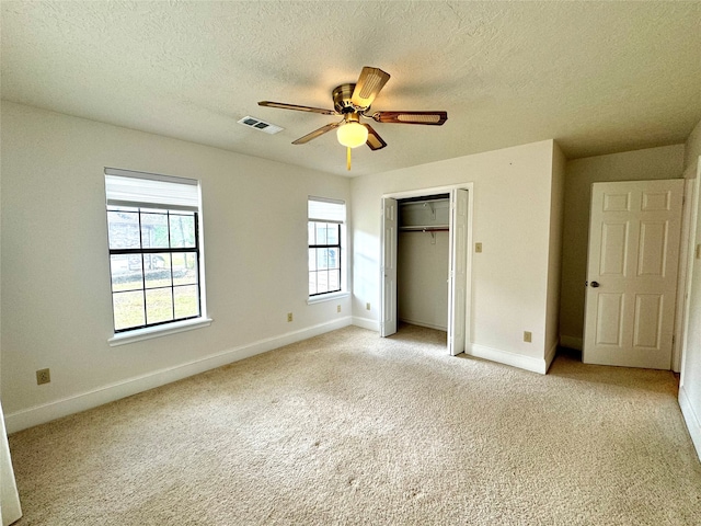 unfurnished bedroom with ceiling fan, a textured ceiling, a closet, and light colored carpet