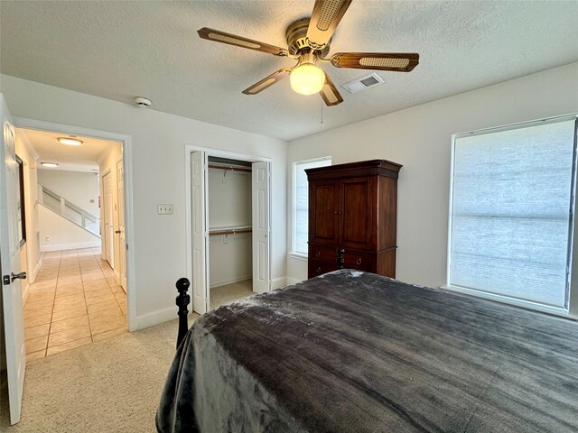 bedroom featuring multiple windows, ceiling fan, a textured ceiling, and light carpet