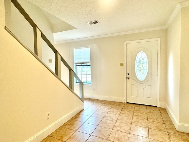 tiled entryway with a textured ceiling and crown molding