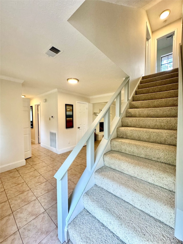 staircase featuring crown molding, a textured ceiling, and tile patterned floors