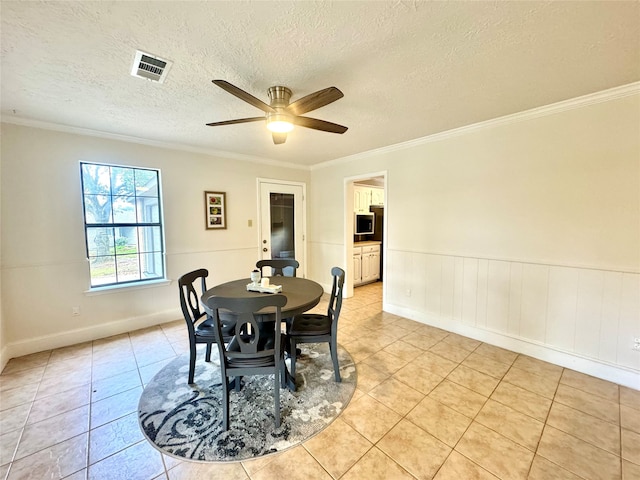 dining space featuring light tile patterned flooring, a textured ceiling, ceiling fan, and crown molding