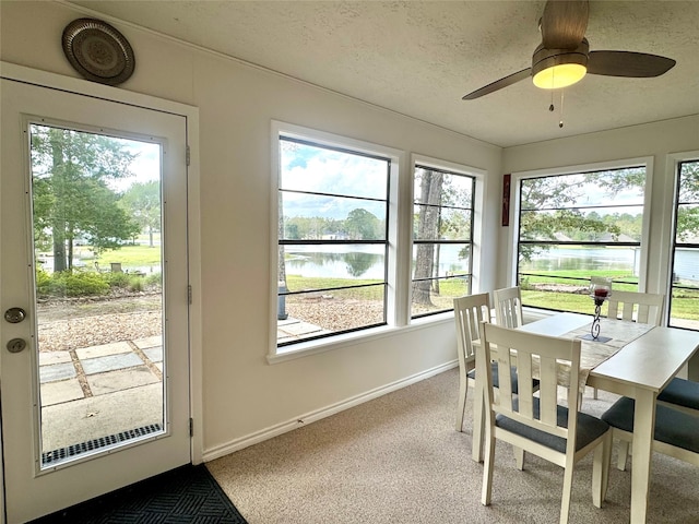 carpeted dining room featuring a textured ceiling, a water view, and ceiling fan