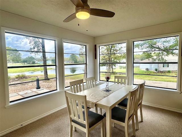 sunroom with a water view and ceiling fan